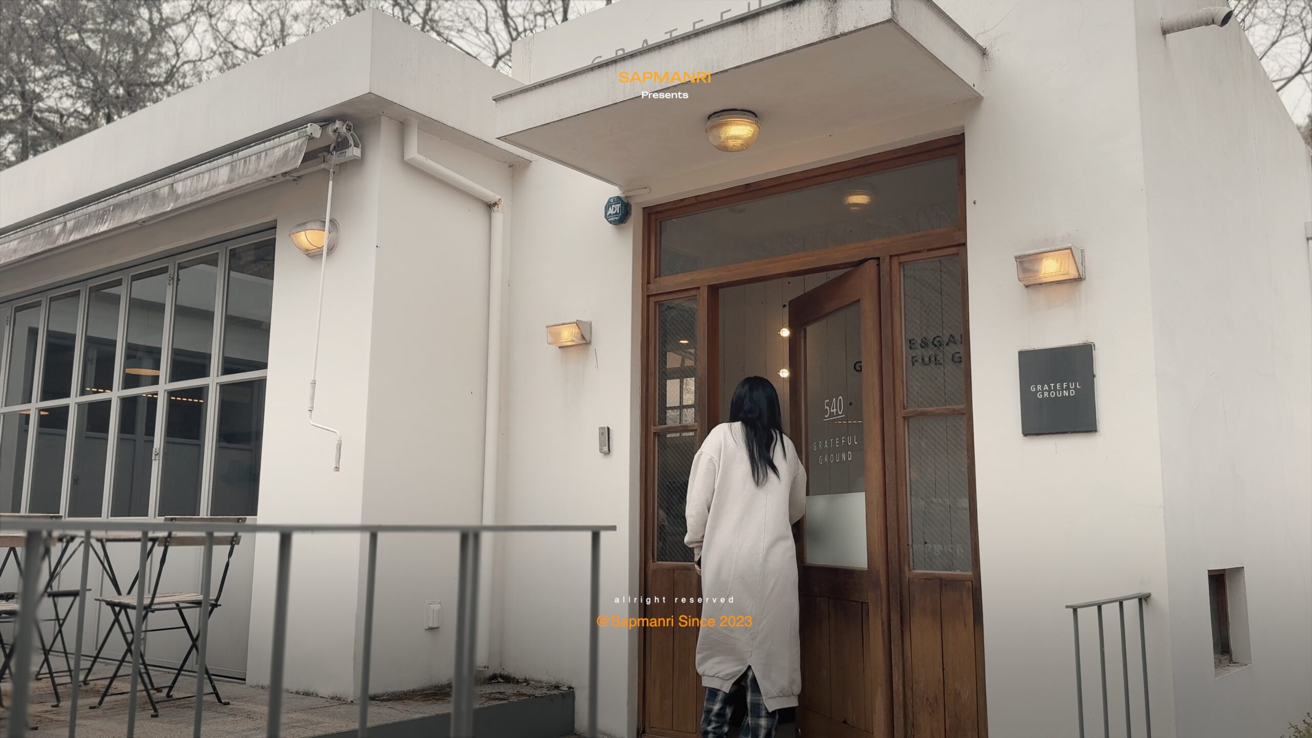 A person entering the white Greatful Ground cafe building in Gapyeong.