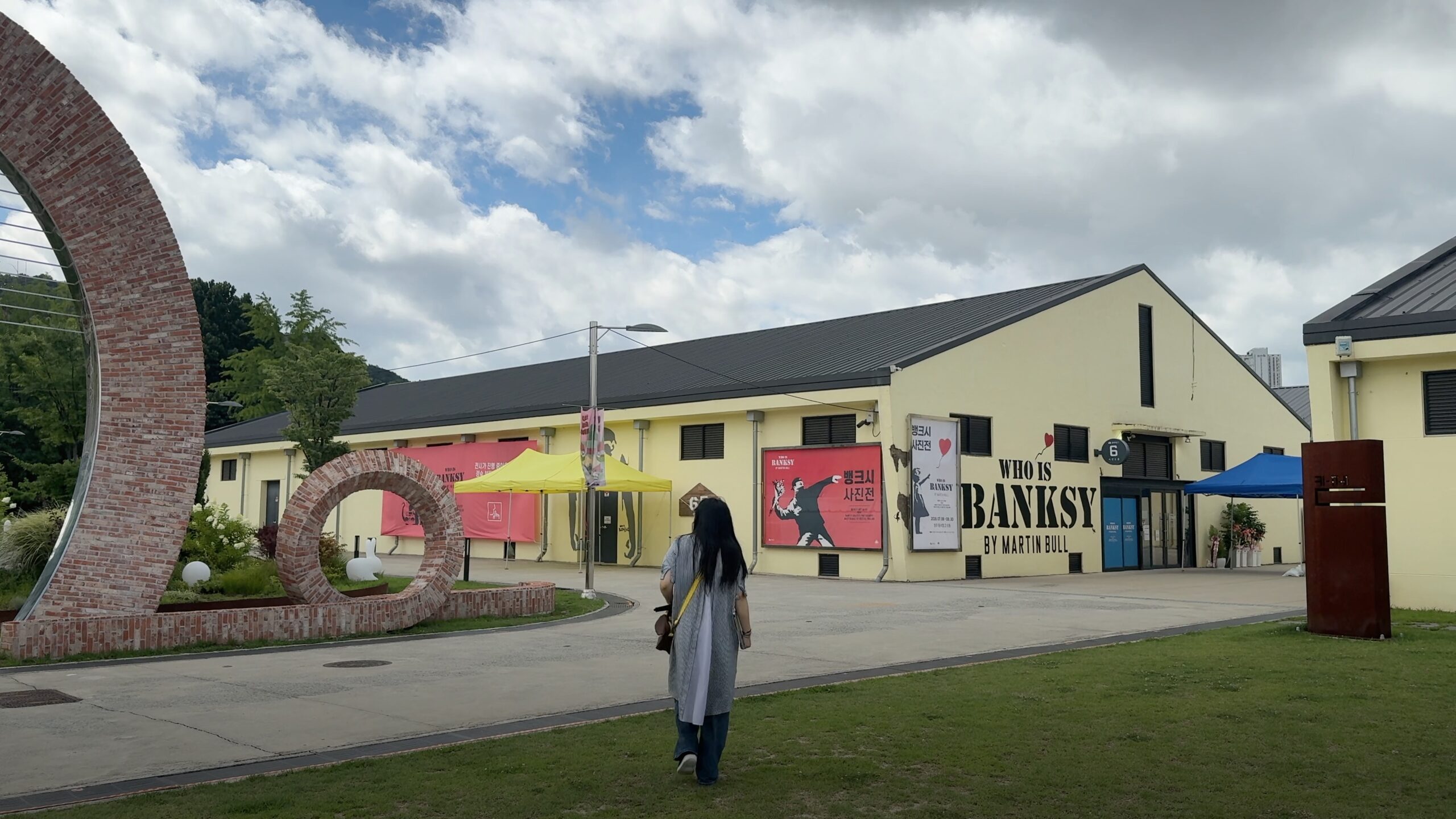 A person walking toward a row of colourful converted warehouse buildings and outdoor artwork.