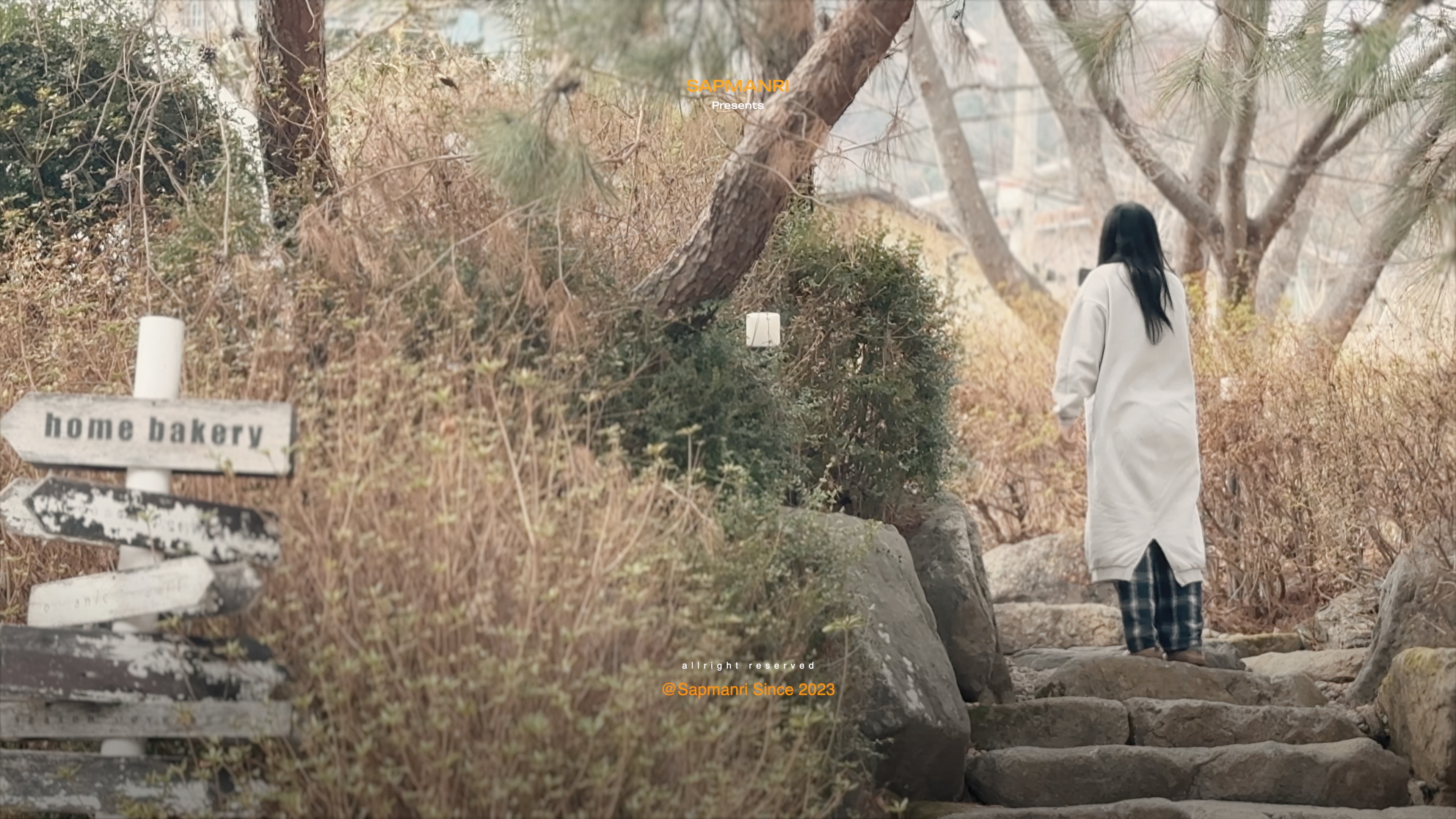 A person walking up uneven stone steps through a dry early-spring garden toward the cafe.