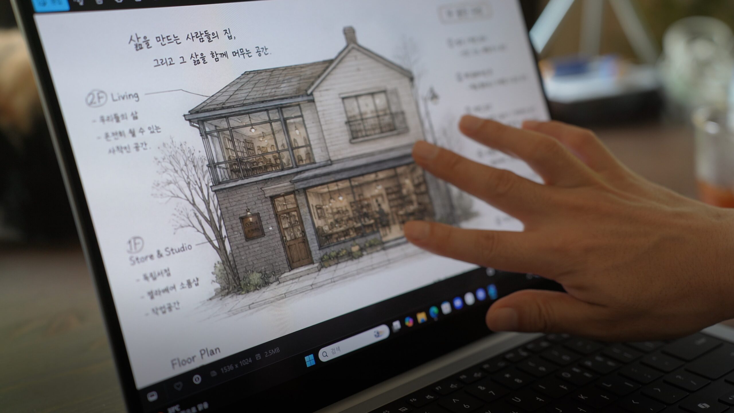 A hand reviewing a two-storey study floor-plan drawing and handwritten Korean notes on a laptop screen.