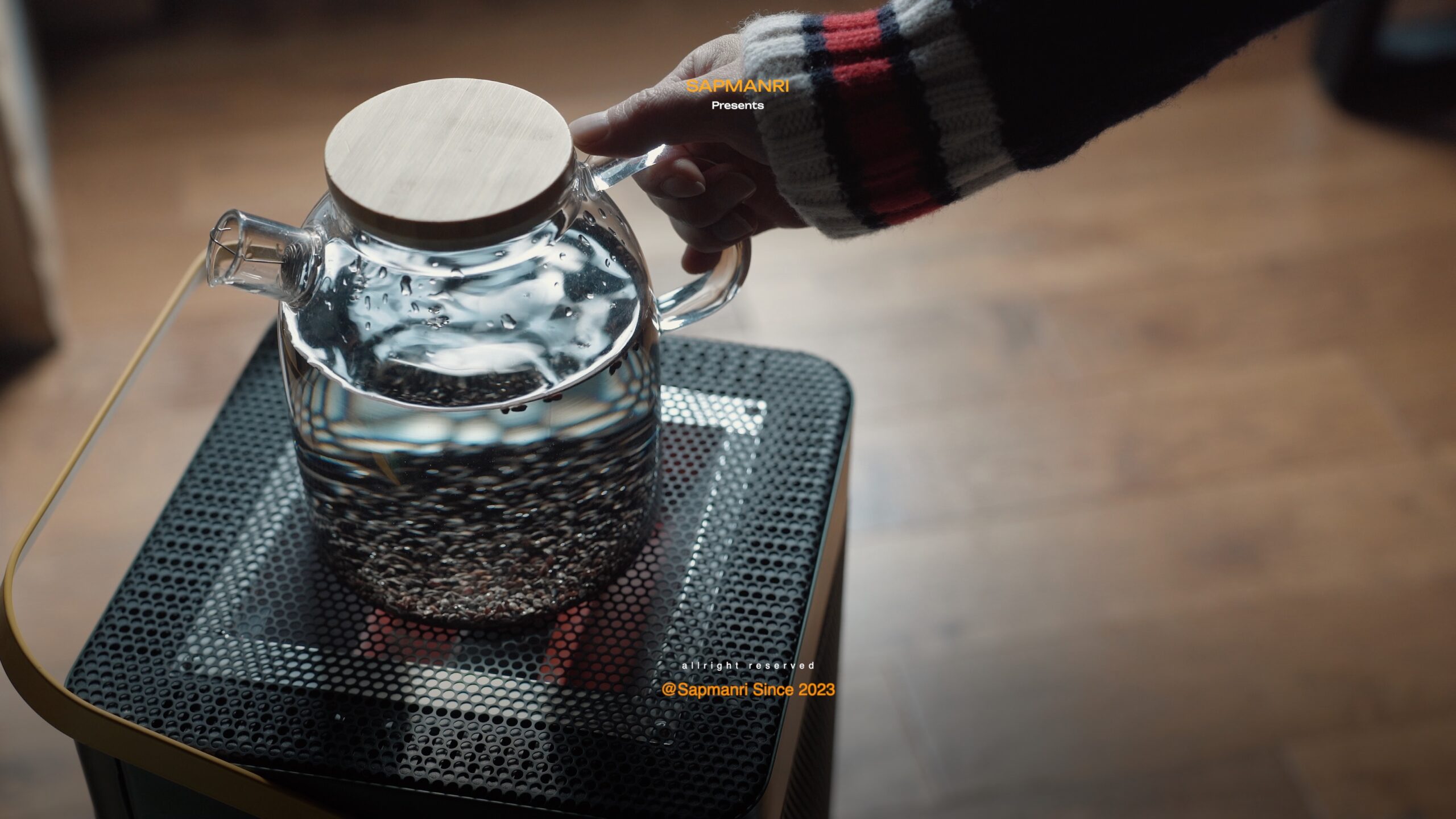 Dark roasted grains steeping in a round glass teapot filled with hot water.