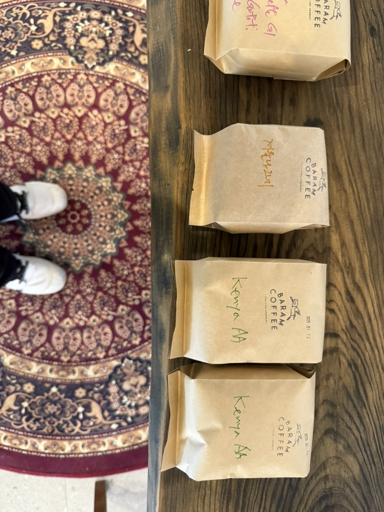 Several sealed paper coffee bags labelled by bean variety on a table.
