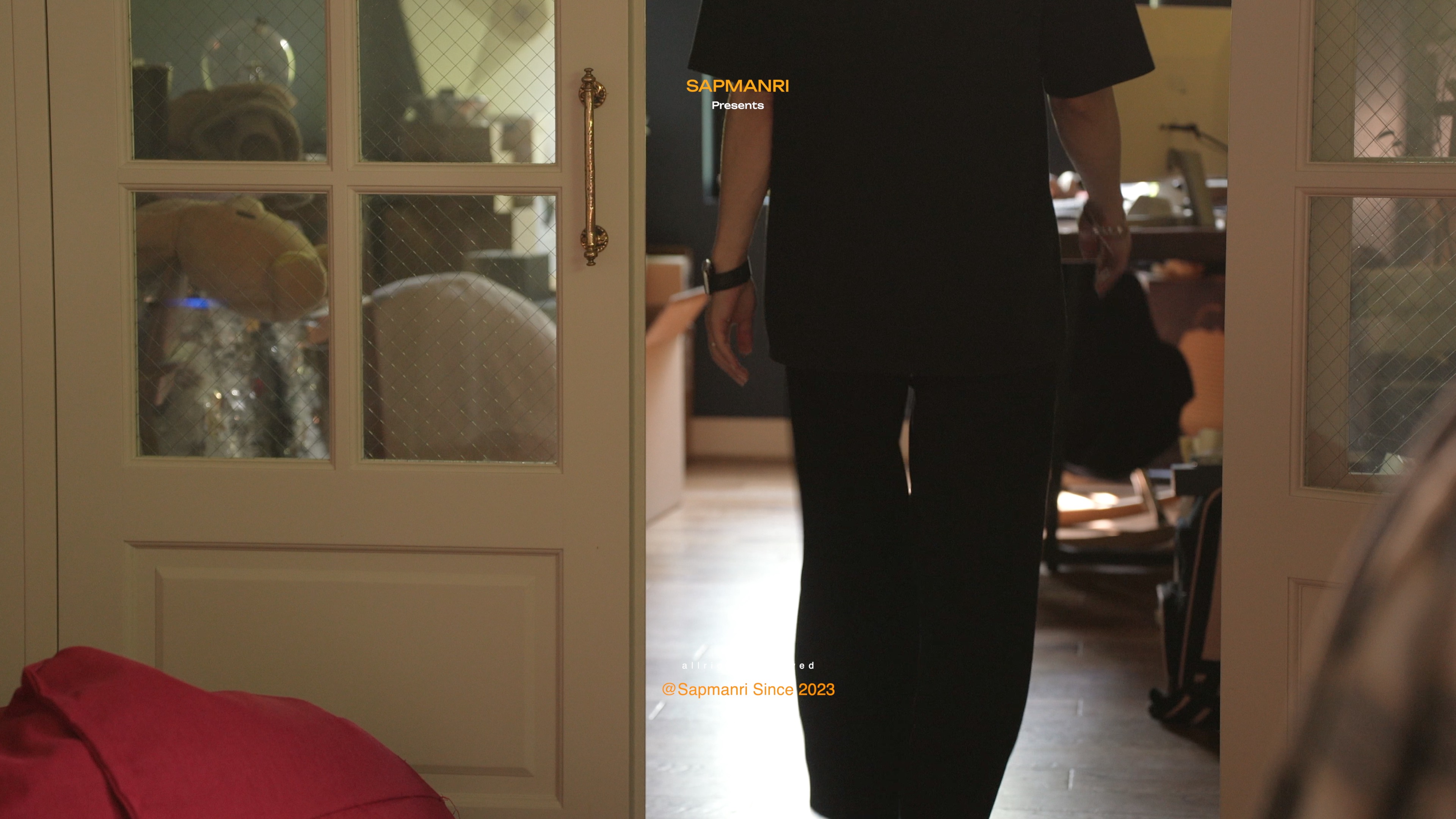 A person dressed in black stepping through white double doors into a room.