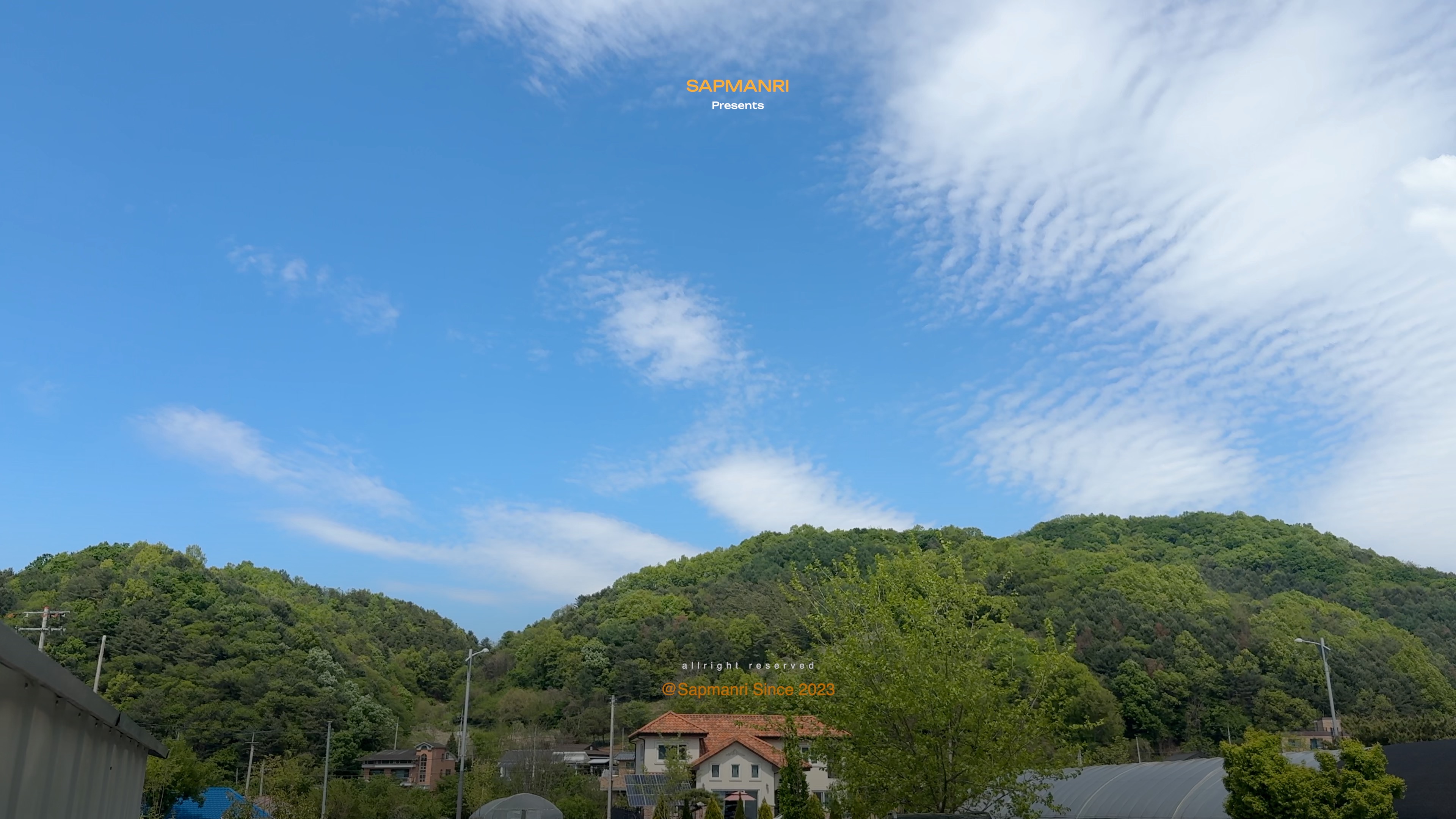 Layered blue mountains beneath a broad sky filled with white spring clouds.