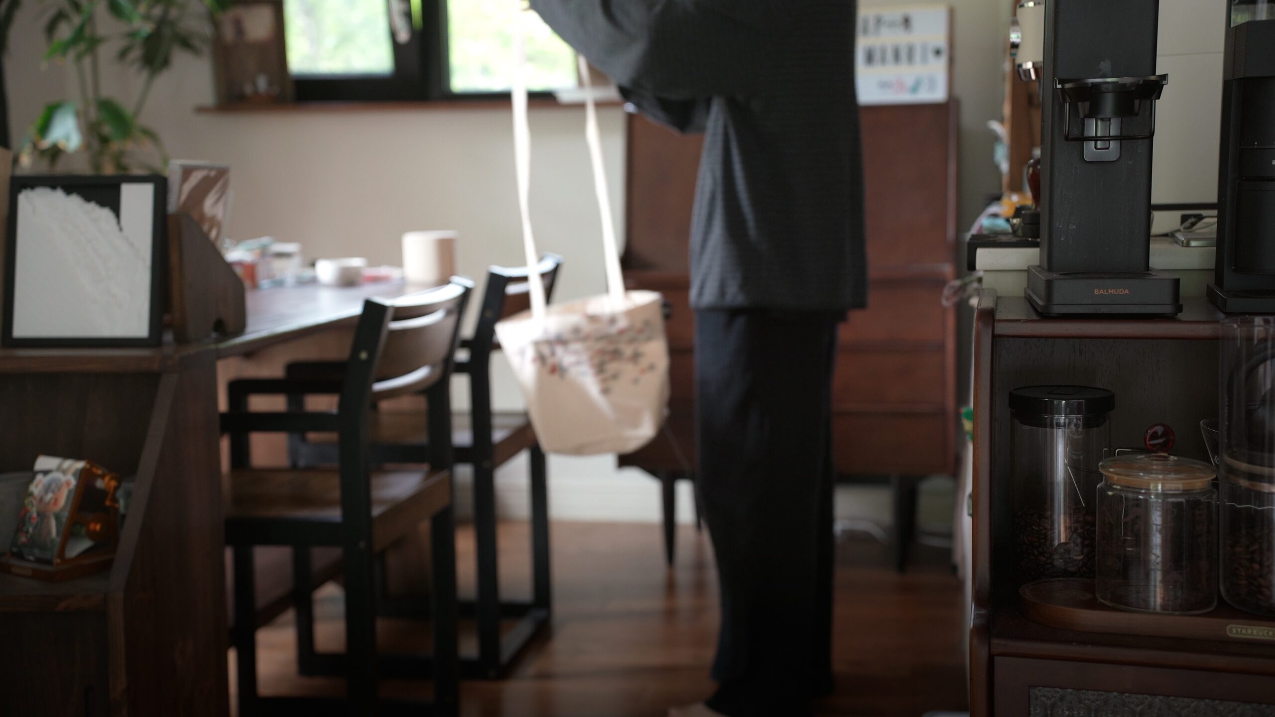 A person wearing the converted canvas tote as a crossbody bag indoors.